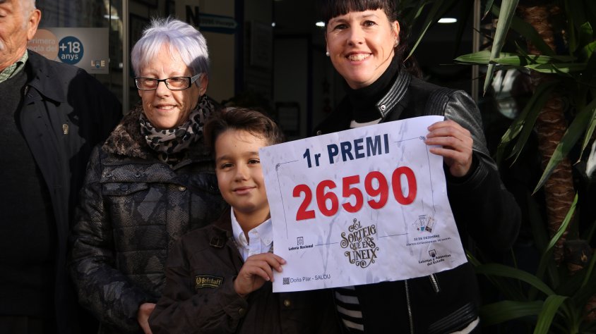 Imatge d'una de les premiades amb la grossa de Nadal a Salou amb un cartell amb el primer premi, el 26590.