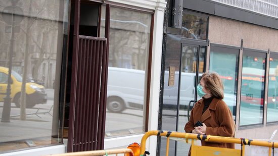 Dona amb mascareta mirant una botiga tancada