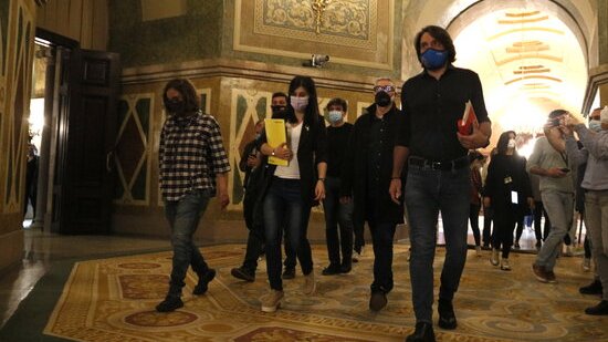 Negociadors d'ERC, Junts i la CUP caminant pels passadissos del Parlament
