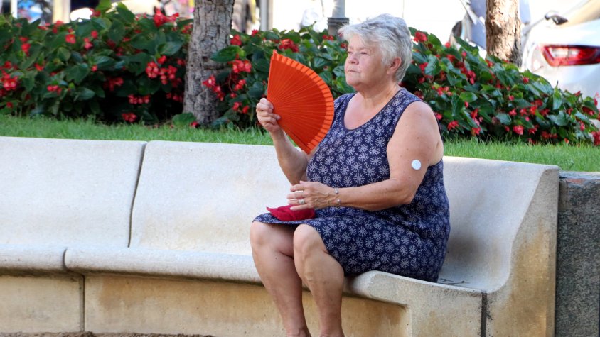 Una dona fent-se vent amb un ventall en una plaça pública de Figueres davant l'onada de calor aquest 2 d'agost de 2018