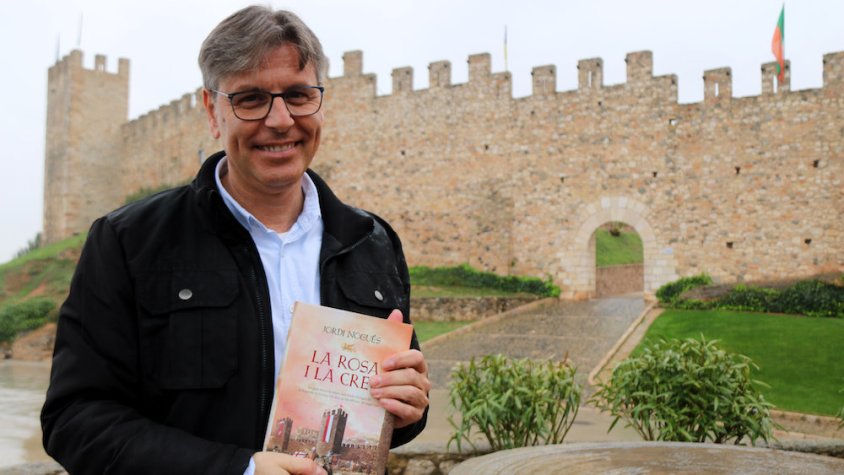 Imatge de l'autor, amb el llibre i davant la muralla de Montblanc